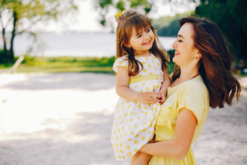 on a sunny beach with yellow sand, mom walks in a yellow dress and her little pretty girl