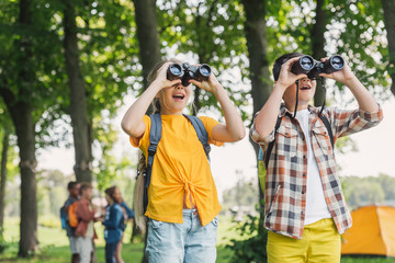 selective focus of happy kids looking through binoculars