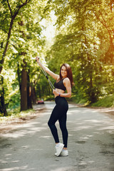 Cute girl training in a summer forest. Lady have fun in a park. Sports woman in a black sportsuit