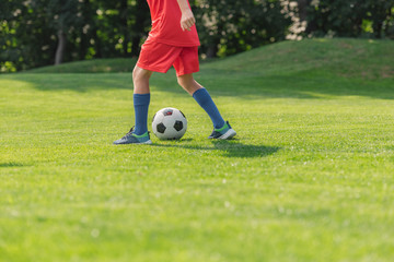Obraz premium selective focus of kid in red sportswear playing football