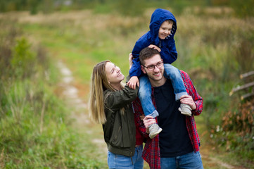 A family of three walks in the village. Copy space