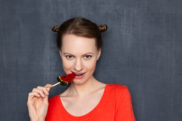 Portrait of cute flirty girl biting lollipop and smiling