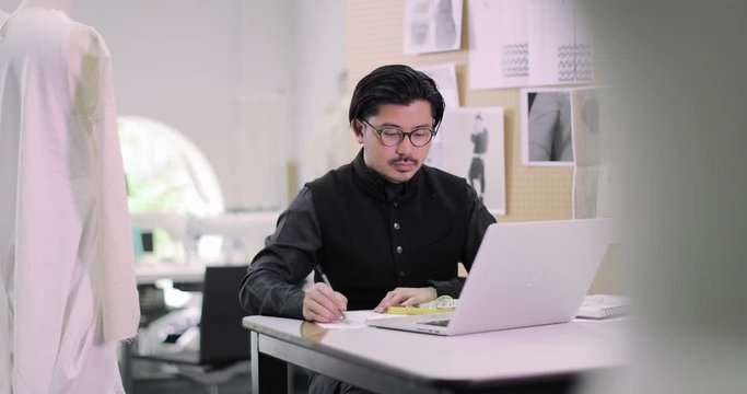 Fashion designer working on pattern with laptop