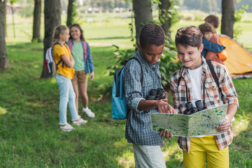 selective focus of african american kid looking at map near friend