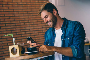 attractive man using mobile phone having a coffee