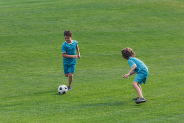 Obraz premium cute boys in sportswear playing football on grass