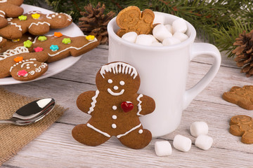 Gingerbread cookies and hot chocolate on a wooden table. Fir in background. Christmas holiday concept.