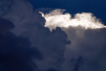 thunderstorm cloudscape with dark cumulus clouds against blue sky