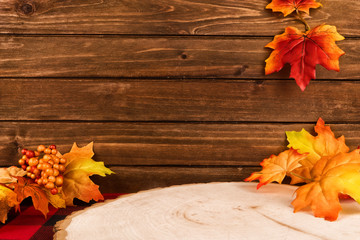 Autumn decor with a wooden plank in background. Maple leaves in decoration. Copy space for your text.