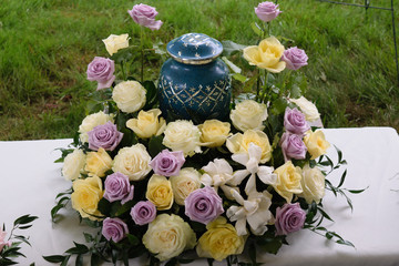 funeral and mourning concept - flowers surrounding urn  - obrazy, fototapety, plakaty