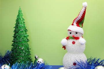 Toy Christmas tree and snowman on green background.