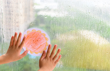 kid holding picture of a smiling sun in a raining day concept of faith and optimism - obrazy, fototapety, plakaty