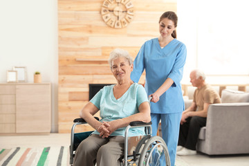 Fototapeta na wymiar Nurse assisting elderly woman in wheelchair at retirement home. Space for text