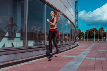 Fototapeta na wymiar Athletic tall and slender beautiful girl runs summer on run, sportswear top leggings, morning afternoon in jump. Active lifestyle, fitness motivation workout. In movement, woman s strong hardy.
