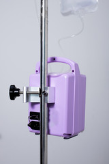 Feeding Pump medical device purple color to supplement nutrition liquid food to tube Enteral feeding fluid set bag with clamp hanging on stand.