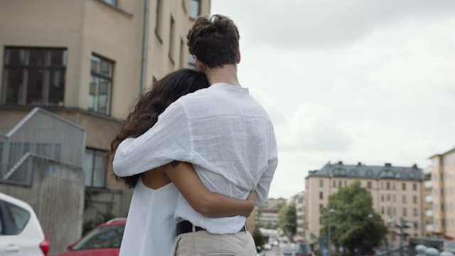 Handheld moving shot of a young loving couple hugging on a street in Stockholm.
