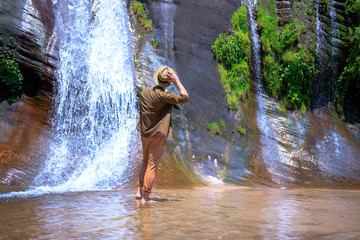 Male tourists wearing hats are enjoying the nature, tourists with waterfalls, beautiful waterfalls