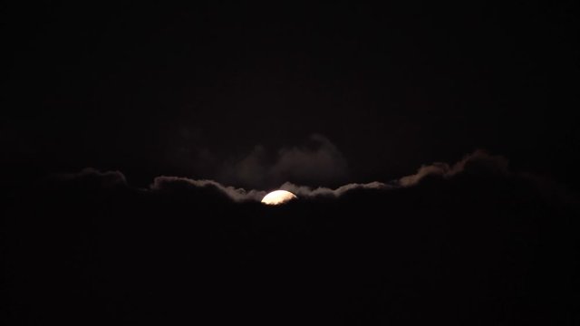 Full Moon Moves in the Night Sky through Dark Clouds. Time lapse. The mystical moon in clouds like waves. Moonlight Shines in the black night sky, 4k footage.