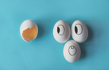 White eggs with faces painted in the shell next to a broken egg