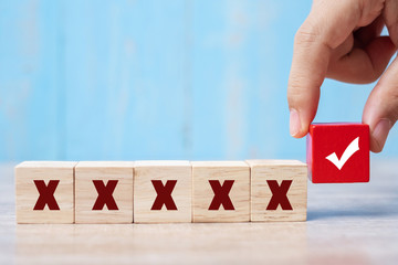 business man holding Wood cubes block with Right symbol different from Wrong symbol on table background
