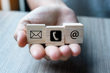 Businessman hand holding wooden block cube symbol email, telephone and address website.  contact, marketing and information concept