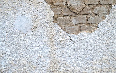 Damaged wall with broken plaster and visible bare bricks.