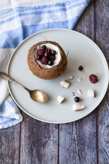Berry dessert with yogurt in a cup of coconut on a wooden background. Blackberries, raspberries, blueberries, black currants.