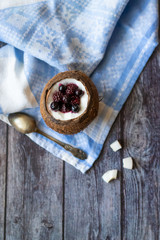 Berry dessert with yogurt in a cup of coconut on a wooden background. Blackberries, raspberries, blueberries, black currants. Blue napkin