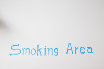 wording smoking area on white concrete wall.