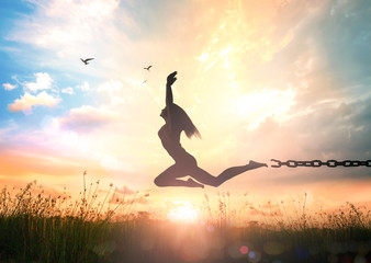 International day for the remembrance of the slave trade and its abolition concept: Silhouette of a girl jumping and broken chains at autumn sunset meadow with her hands raised - obrazy, fototapety, plakaty