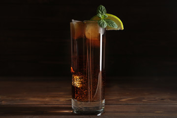 Glass of fresh cola with ice on wooden table