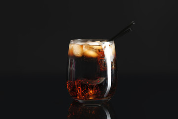Glass of fresh cola with ice on dark background