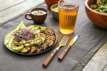 Plate with tasty salad and glass of juice on table