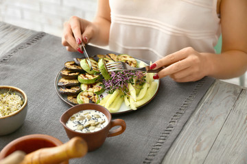Woman eating tasty salad at table, closeup
