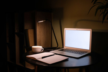 Modern workplace with laptop in evening