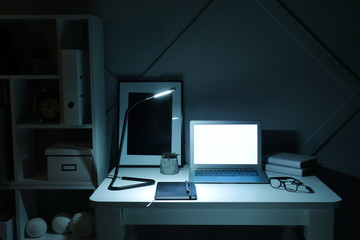 Modern workplace with laptop in evening