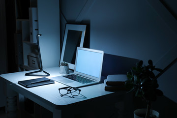 Modern workplace with laptop in evening