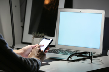 Woman with mobile phone working at table in evening
