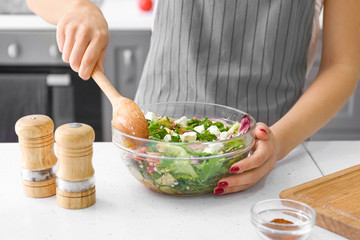 Woman preparing fresh salad at table, closeup