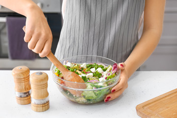 Woman preparing fresh salad at table, closeup
