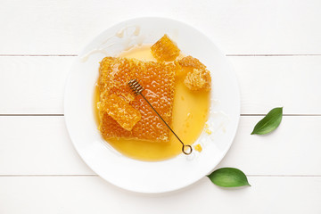 Plate with honey combs on white wooden background