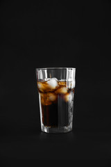 Glass of cold cola on dark background