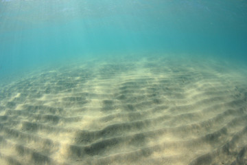 Sandy sea floor and underwater blue background