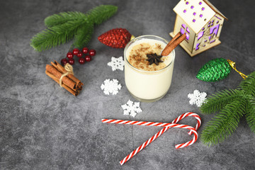 Eggnog delicious holiday drinks like themed parties with cinnamon pine cone and nutmeg for Traditional Christmas and winter holidays Homemade eggnog in glasses candy cane decorated table