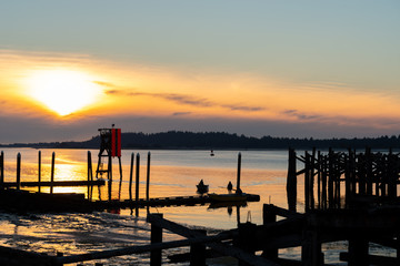 Fototapeta na wymiar Sunset at Coos Bay Oregon Empire dock. Silhouetted wood pilings, industrial fishing wharf.
