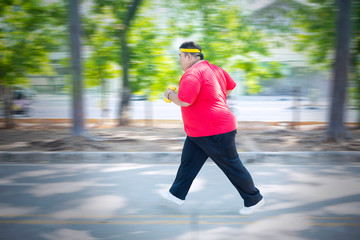 Fat man holding dumbbells and sprinting in park