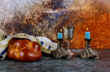 Shabbat eve with challah bread, Sabbath candles and kiddush wine cup.