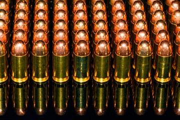 Neat Rows of handgun ammunition on black background with reflection