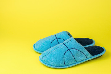 Blue Slippers with embroidery on a yellow background.