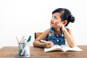 School kid little girl learning and writing in notebook with pencil making homework at home.Education concept